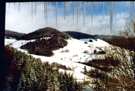 Ausblick ins verschneite Tal aus einem Fenster im Obergeschoss